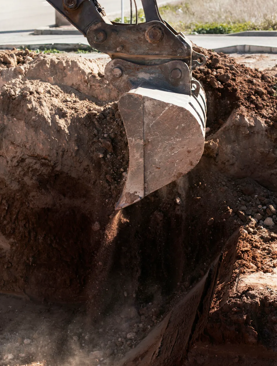 Excavator bucket digging a deep trench for basement excavation and foundation preparation in Dallas TX